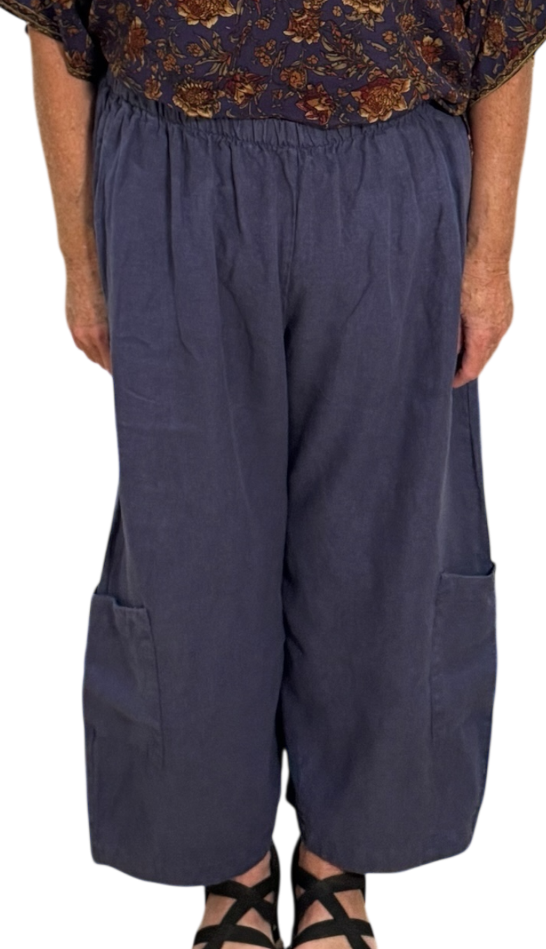 Woman wearing a floral top and navy harem pants on a white background