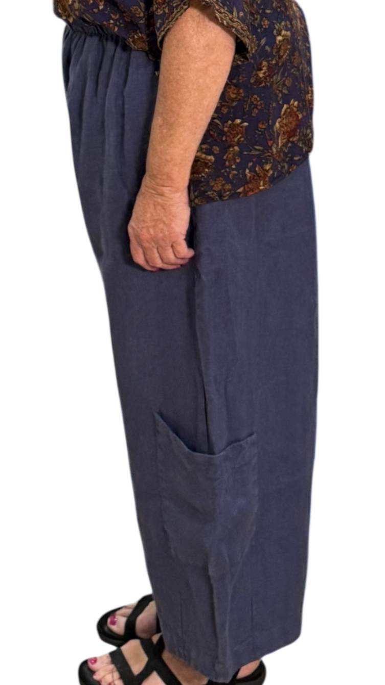 Woman wearing a patterned top and dark pants on a white background