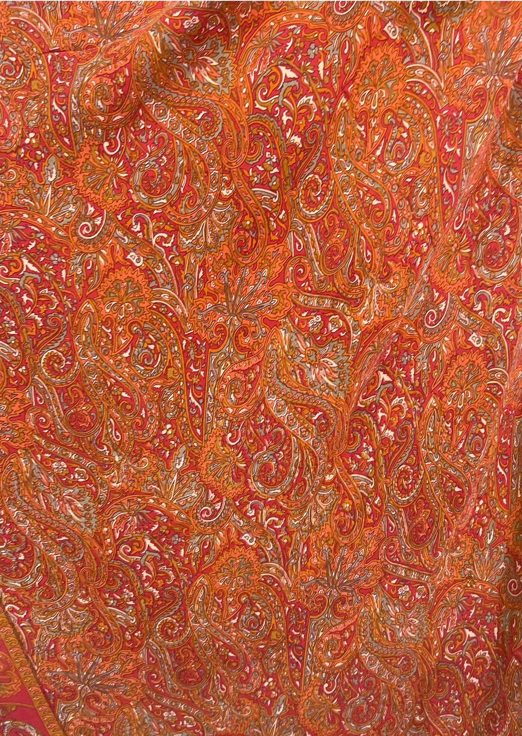 Close-up of a patterned fabric with intricate designs in red and orange.